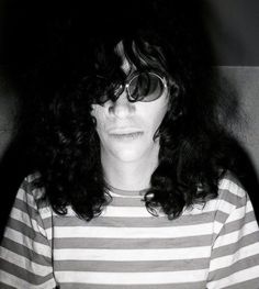 black and white photograph of a woman with long curly hair wearing sun glasses, looking at the camera