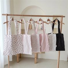 several bags hanging on a wooden rack in front of a wall with white and black polka dots