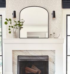 a white fireplace with a mirror above it