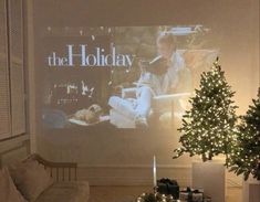 a living room with christmas trees and presents on the table in front of a large screen