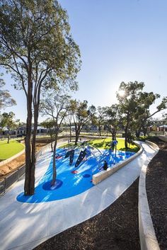 an empty playground with water slides and trees in the foreground, on a sunny day