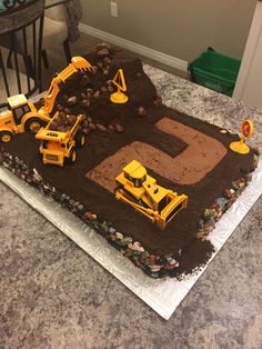 a birthday cake made to look like a construction site with dump trucks and tractors on it