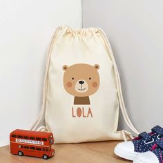 a bag with a teddy bear on it next to a pair of sneakers and a toy bus