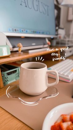 a cup of coffee sitting on top of a desk next to a keyboard and monitor