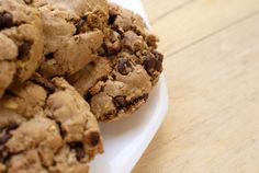 chocolate chip cookies stacked on top of each other in a white plate with a wooden table