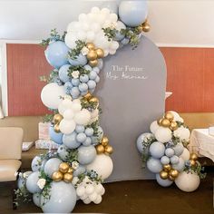 the balloon arch is decorated with blue and white balloons, greenery, and gold accents