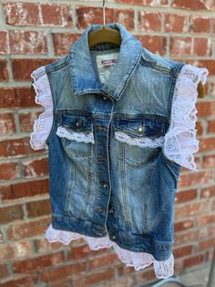 a denim vest hanging on a brick wall