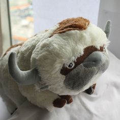 a stuffed animal that is laying down on a white sheet with the head turned to look like an oxen