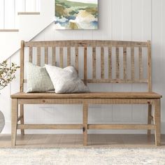 a wooden bench sitting in front of a stair case next to a vase with flowers