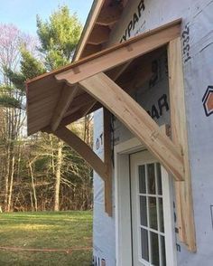 a house under construction with wood framing on the roof and siding around the porch area