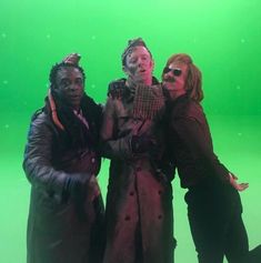 three people standing together in front of a green screen