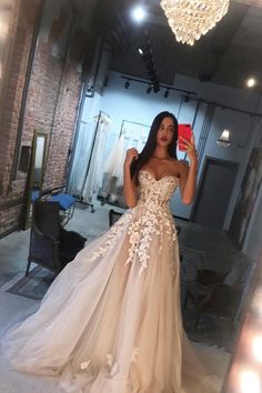 a woman in a wedding dress taking a selfie with her cell phone while standing in front of a mirror