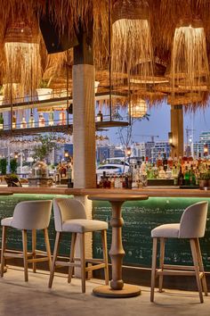 a bar with chairs and straw umbrellas hanging from the ceiling over it's bar