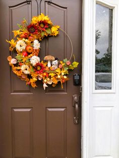 a front door with a wreath decorated with fall leaves, pumpkins and gourds