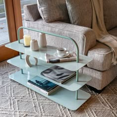 a living room with a couch, coffee table and books on the floor next to a window