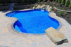 a swimming pool surrounded by stone steps and landscaping