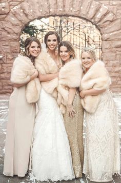 four bridesmaids in long dresses and fur stoles posing for a photo together