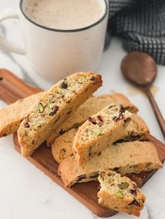 several pieces of biscuit on a cutting board next to a cup of coffee