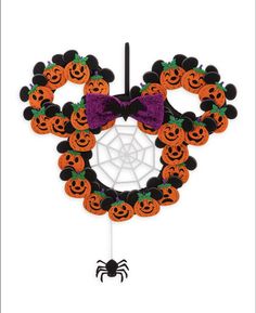 a mickey mouse halloween wreath with pumpkins and spider web on the front, hanging from a hook