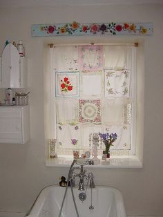 a white sink sitting under a window next to a bathtub with flowers on it