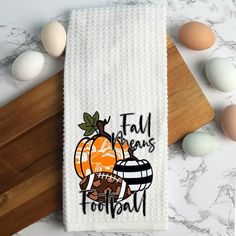 a towel with an image of a football and pumpkin on it next to some eggs