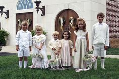 a group of young children standing next to each other in front of a church door