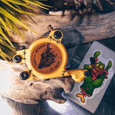 a yellow clock sitting on top of a wooden table next to a plant and sticker