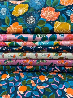 a stack of colorful fabrics with flowers on them, all in different colors and sizes