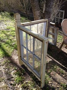 an old window sitting in the grass next to a chair