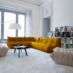 a living room filled with furniture next to a large window and a white rug on the floor