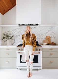 a woman standing in front of an oven with her feet up on the stove top