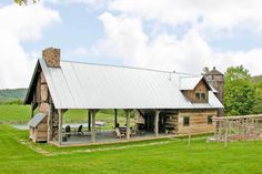 a rustic log cabin sits in the middle of a grassy field with a picnic table