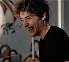 a young man laughing in front of a clock