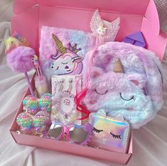 a pink box filled with lots of toys and decorations on top of a white bed