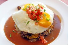 an egg is sitting on top of some rice with sauce and garnishes