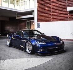 a blue sports car parked in front of a building