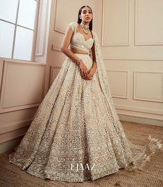 Ramp up your look with this exquisite ivory ornamented lehenga set. Crafted from foil net-silk, the lehenga is adorned with sequins and stones stitched ornately all over. The sweetheart neckline studded blouse oozes glamour and sophistication. The sheer net dupatta completes this showstopping ensemble for a look that will be remembered.Available at BIBI London. To book your appointment, call us at 07931 999111. Ejaaz Couture, Golden Bridal Lehenga, Ivory Lehenga, Ivory Bride, Indian Wedding Gowns, Reception Outfit, Reception Lehenga