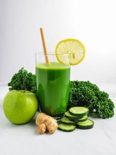 a green smoothie in a glass surrounded by sliced cucumbers