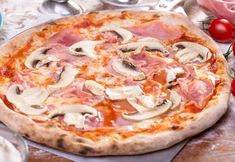 a pizza sitting on top of a table covered in toppings next to tomatoes and mushrooms