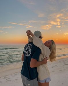 a man and woman hug on the beach at sunset