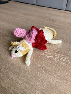 a small crocheted mouse laying on top of a wooden table