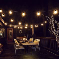 an outdoor dining area with string lights strung across the ceiling and table set for four