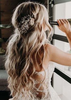 a woman in a wedding dress looking out the window with her hair comb in her hand