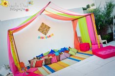 a bed with colorful sheets and pillows on top of it in front of a white wall