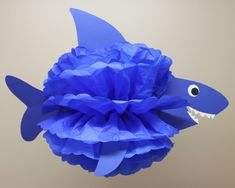 a blue paper fish decoration hanging from the ceiling with its mouth wide open and it's tongue out