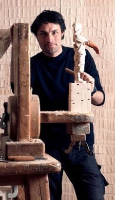 a man standing next to a wooden sculpture