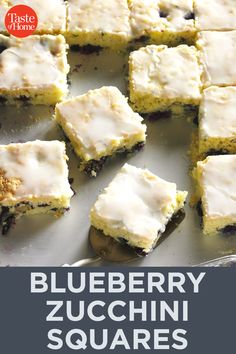 blueberry zucchini squares with white icing on a baking sheet, ready to be eaten