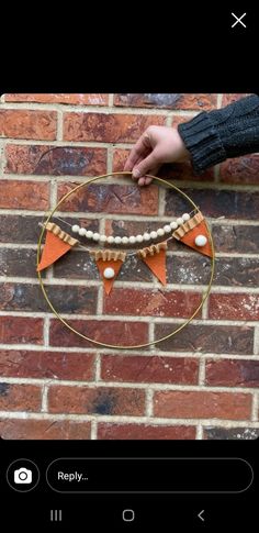 a person holding onto a hoop with orange and white decorations hanging from it on a brick wall