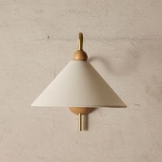 a wall light with a white shade hanging from it's side on the wall