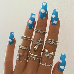 a woman's hand with blue and white nail polish holding five different types of rings